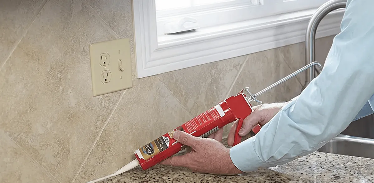 Handyman applying caulk along a kitchen backsplash and countertop seam in Cape Coral, FL